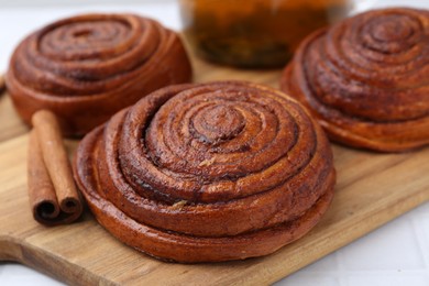 Photo of Delicious cinnamon rolls and stick on white tiled table, closeup