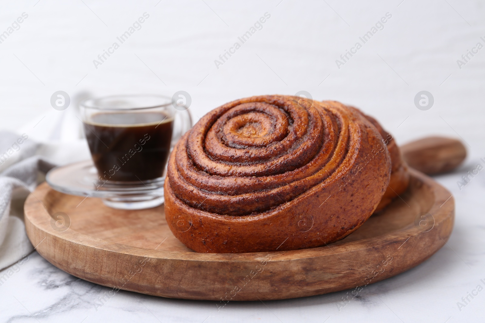 Photo of Delicious cinnamon roll and coffee on white marble table, closeup