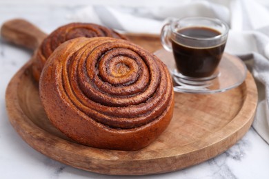 Photo of Delicious cinnamon rolls and coffee on white marble table, closeup