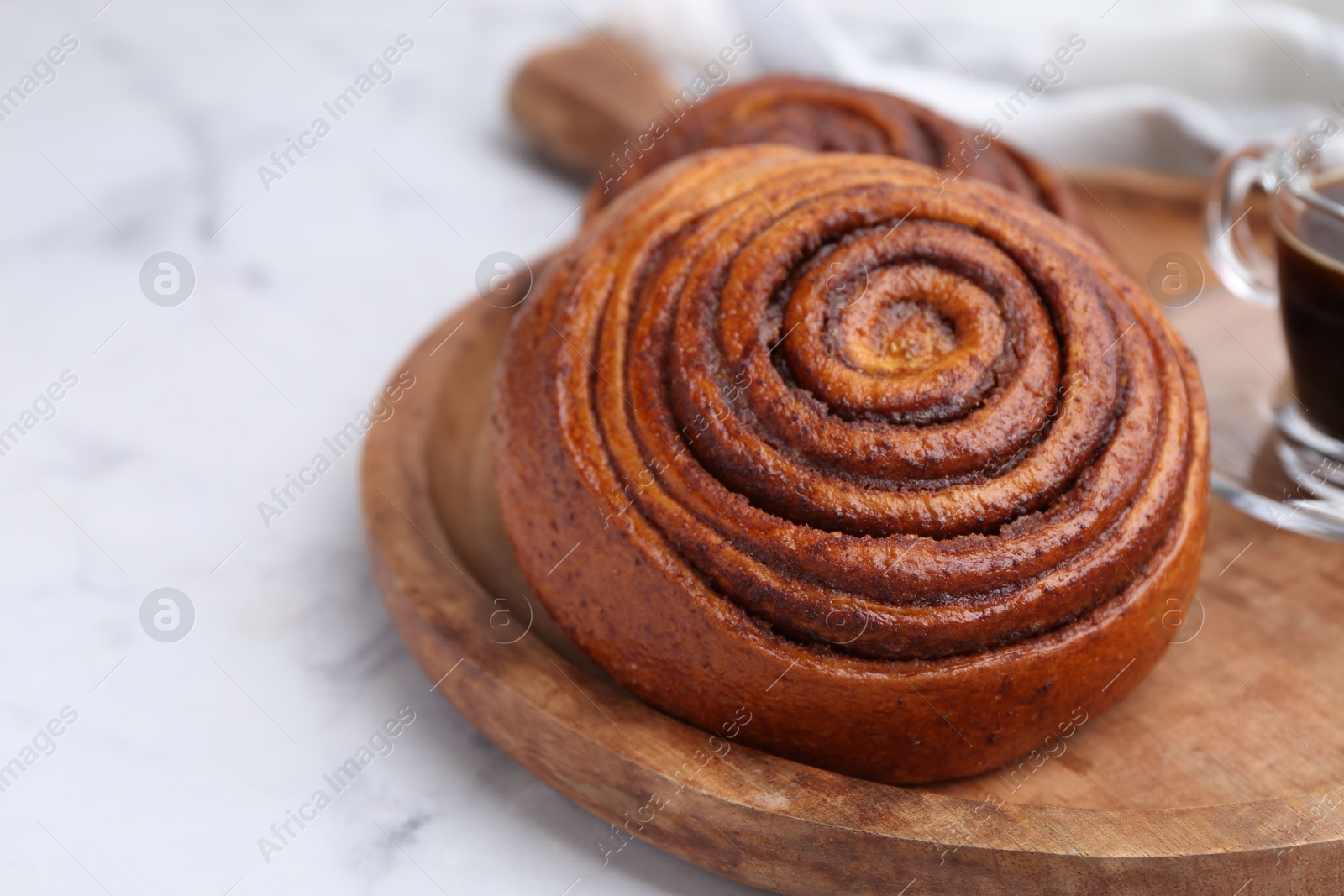 Photo of Delicious cinnamon roll on white marble table, closeup. Space for text