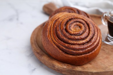 Photo of Delicious cinnamon roll on white marble table, closeup. Space for text