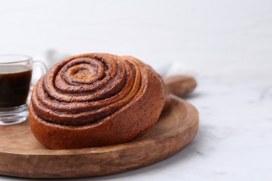 Photo of Delicious cinnamon roll on white marble table, closeup. Space for text