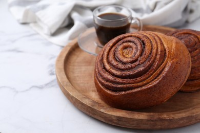 Photo of Delicious cinnamon rolls on white marble table, closeup. Space for text