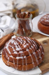 Photo of Tasty cinnamon roll with cream on white table, closeup