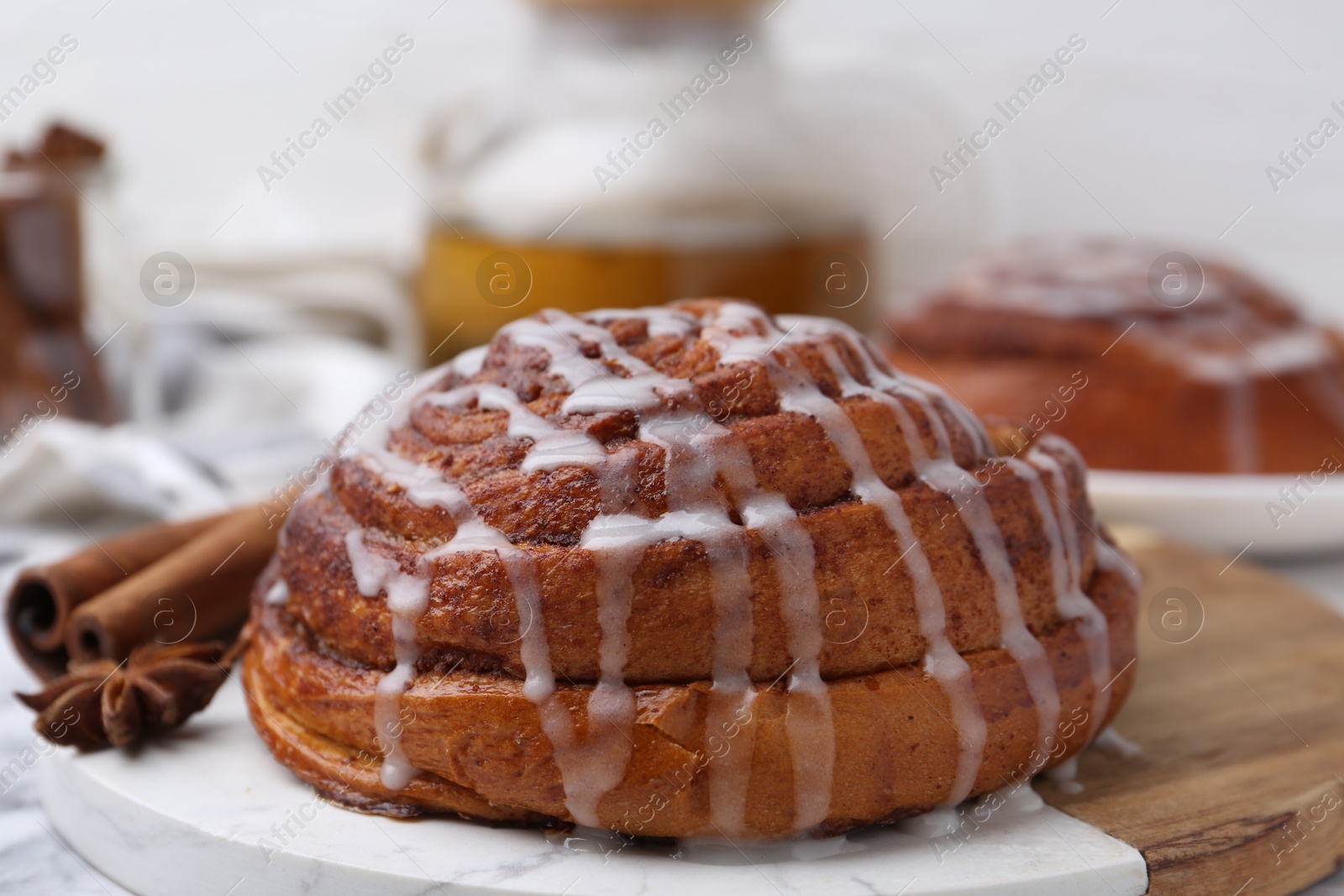 Photo of Tasty cinnamon roll with cream and spices on white table, closeup