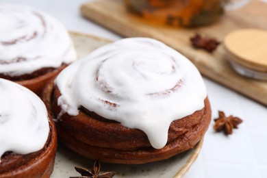 Photo of Tasty cinnamon rolls with cream and spices on white table, closeup