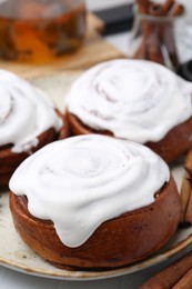 Photo of Tasty cinnamon rolls with cream on white table, closeup