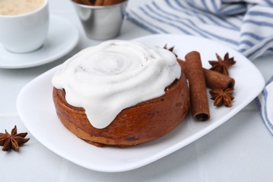 Photo of Tasty cinnamon roll with cream, spices and coffee on white table, closeup