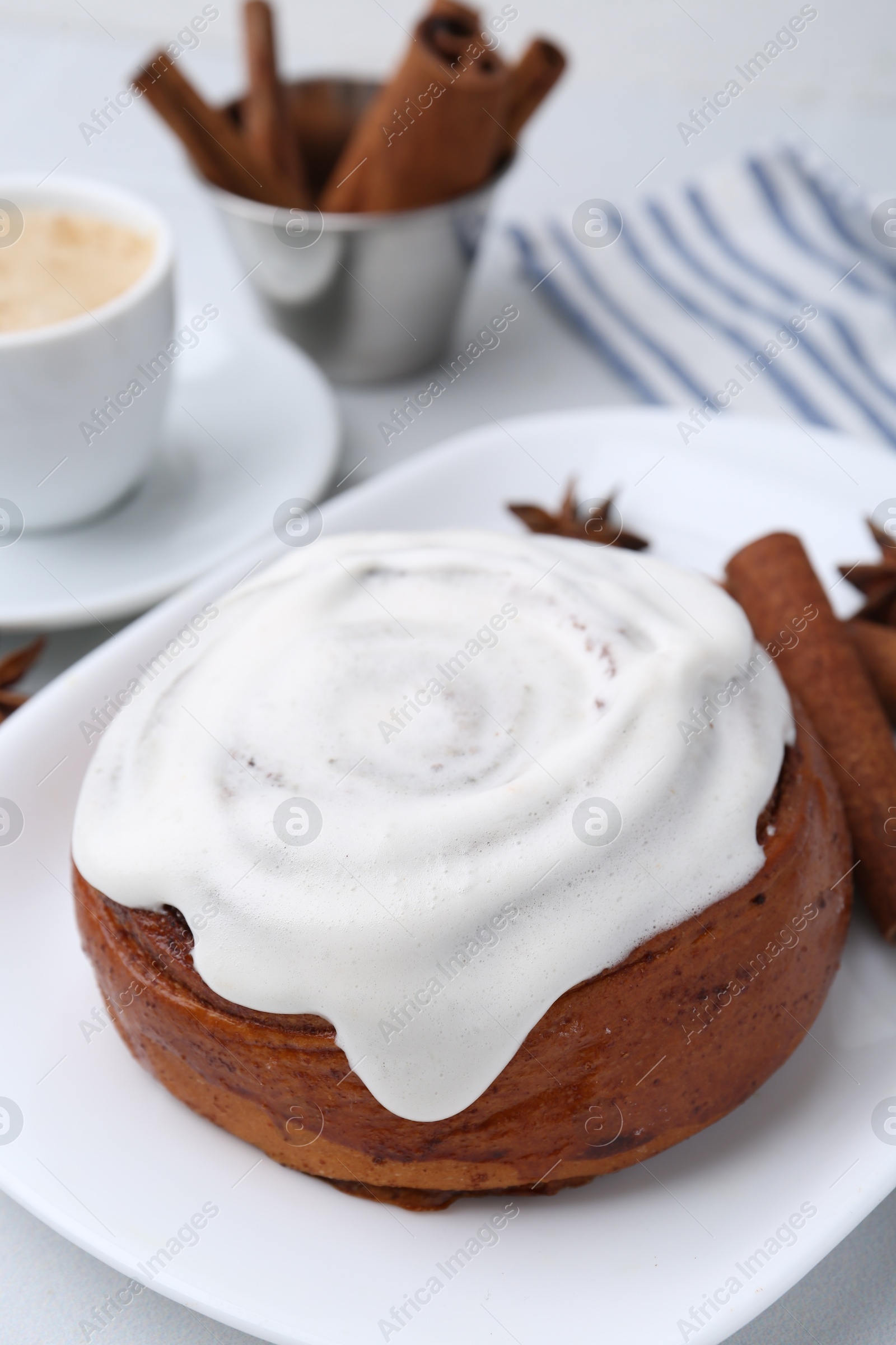 Photo of Tasty cinnamon roll with cream, spices and coffee on white table, closeup