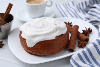 Photo of Tasty cinnamon roll with cream, spices and coffee on white tiled table, closeup