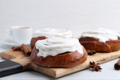 Photo of Tasty cinnamon rolls with cream and spices on white table, closeup