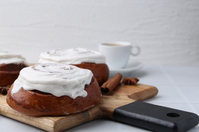 Photo of Tasty cinnamon rolls with cream on white table, closeup