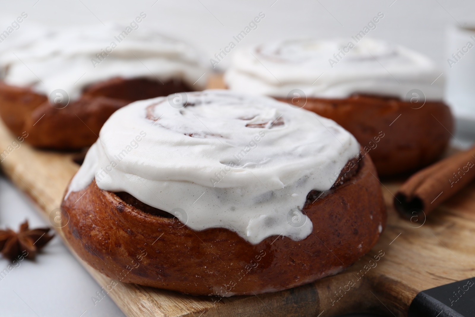 Photo of Tasty cinnamon rolls with cream on white table, closeup