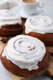 Photo of Tasty cinnamon rolls with cream on white table, closeup