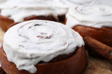 Photo of Tasty cinnamon rolls with cream as background, closeup