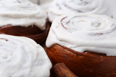 Photo of Tasty cinnamon rolls with cream as background, closeup