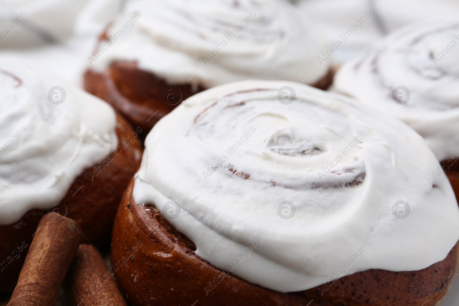 Photo of Tasty cinnamon rolls with cream as background, closeup