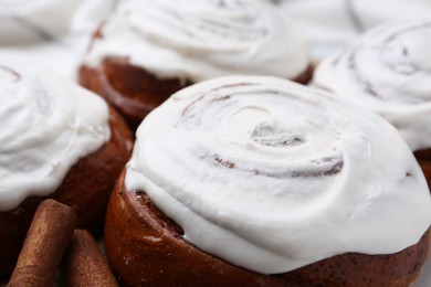 Photo of Tasty cinnamon rolls with cream as background, closeup