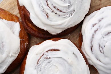 Photo of Tasty cinnamon rolls with cream as background, closeup