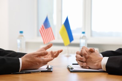 Photo of Diplomats negotiating during meeting at table indoors, closeup