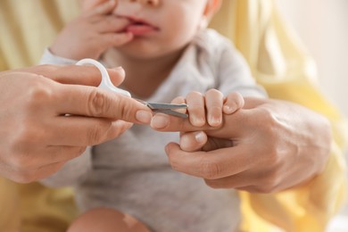 Photo of Mother cutting her cute little baby's nails at home, closeup