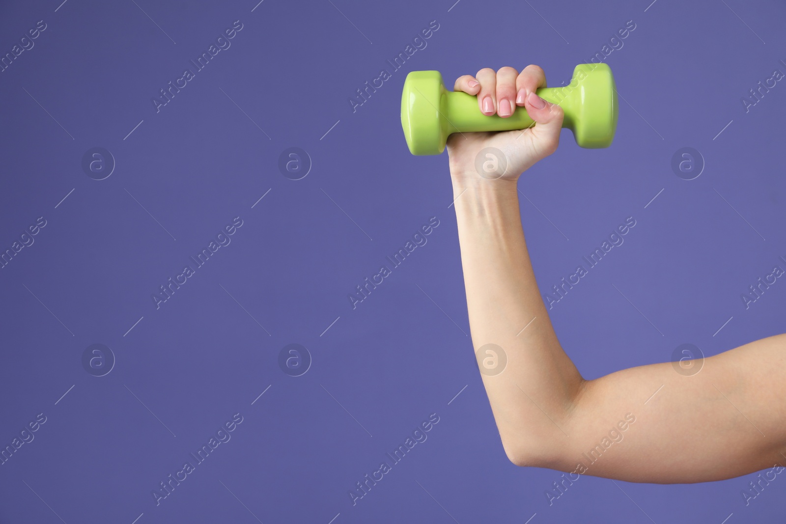 Photo of Woman exercising with dumbbell on purple background, closeup. Space for text