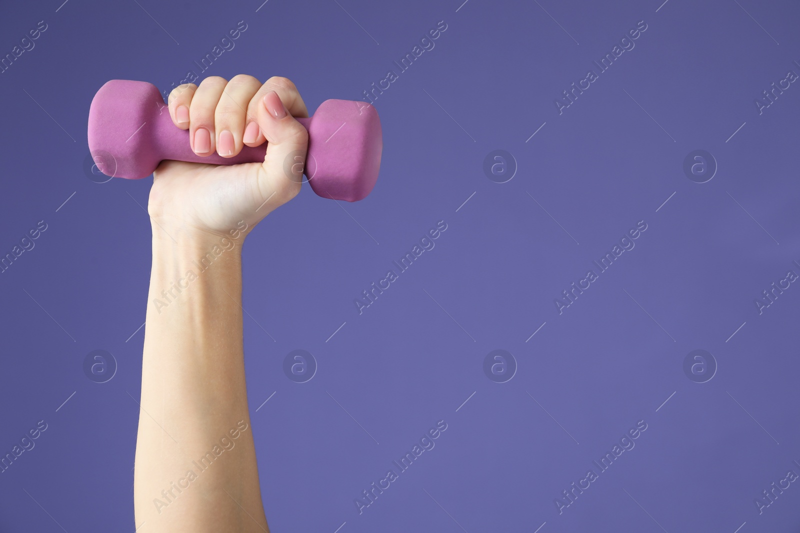 Photo of Woman exercising with dumbbell on purple background, closeup. Space for text