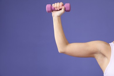 Photo of Woman exercising with dumbbell on purple background, closeup. Space for text