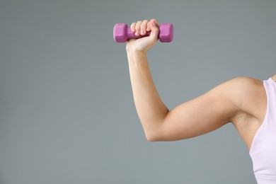 Photo of Woman exercising with dumbbell on light grey background, closeup. Space for text