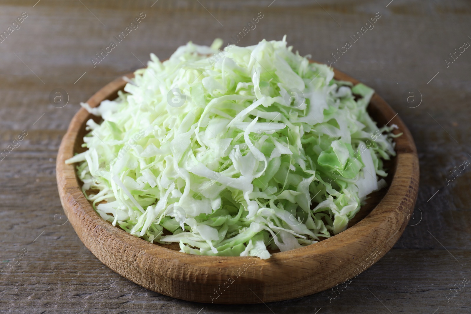 Photo of Fresh shredded cabbage on wooden table, closeup