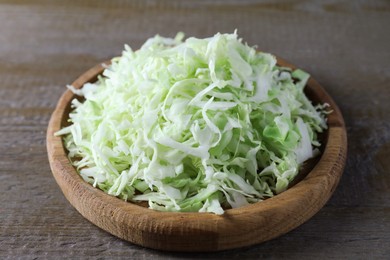 Photo of Fresh shredded cabbage on wooden table, closeup