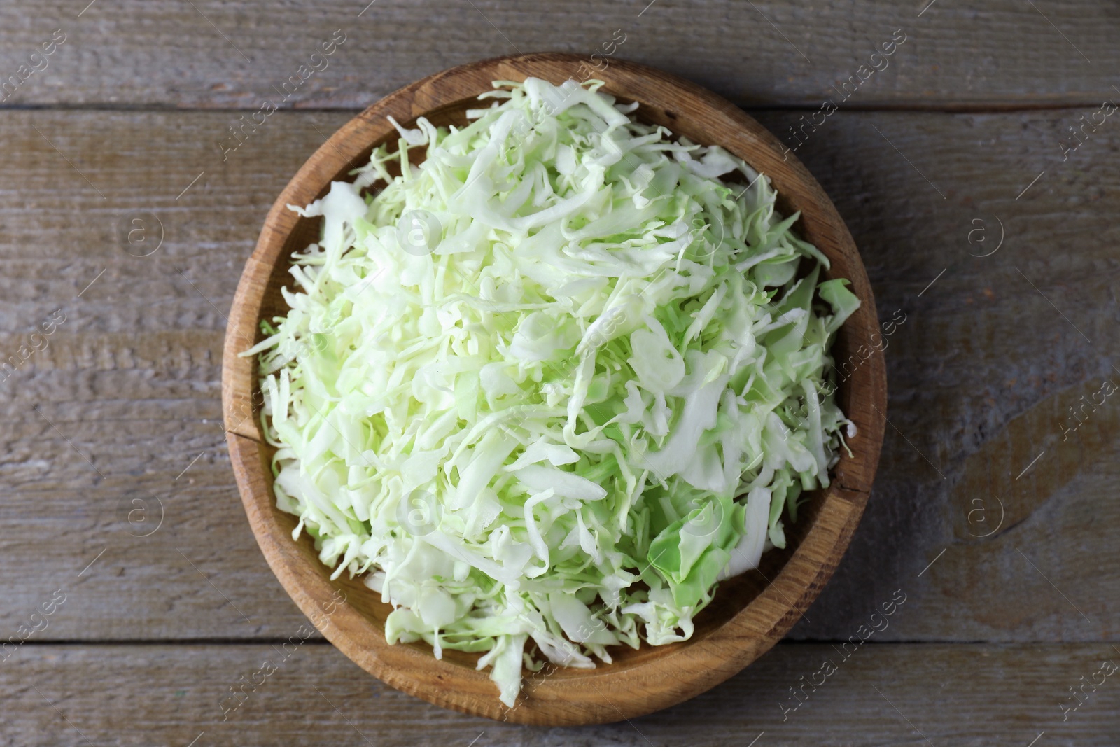 Photo of Fresh shredded cabbage on wooden table, top view