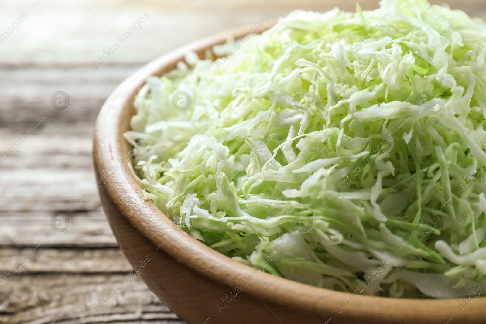 Photo of Fresh shredded cabbage on wooden table, closeup