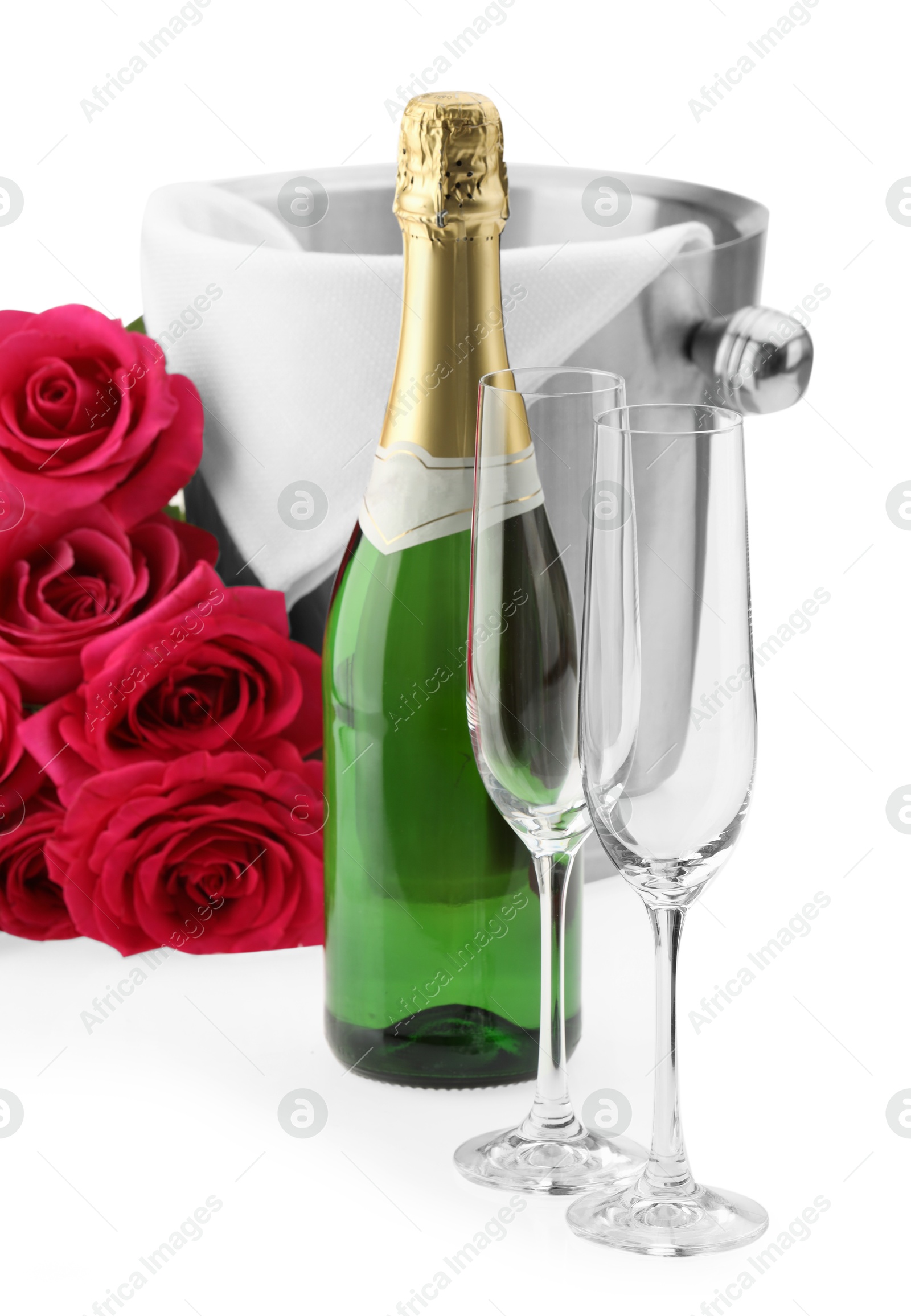 Photo of Bottle of champagne, empty glasses, beautiful roses and ice bucket isolated on white