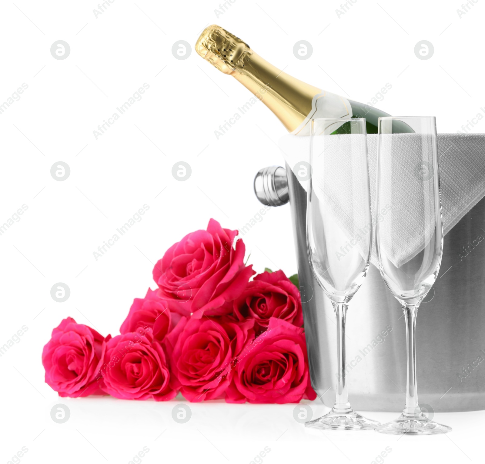 Photo of Bottle of champagne in ice bucket, beautiful roses and empty glasses isolated on white