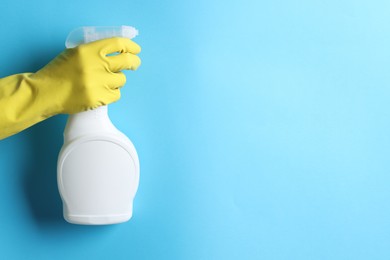 Photo of Woman with spray bottle of cleaning product on light blue background, closeup. Space for text