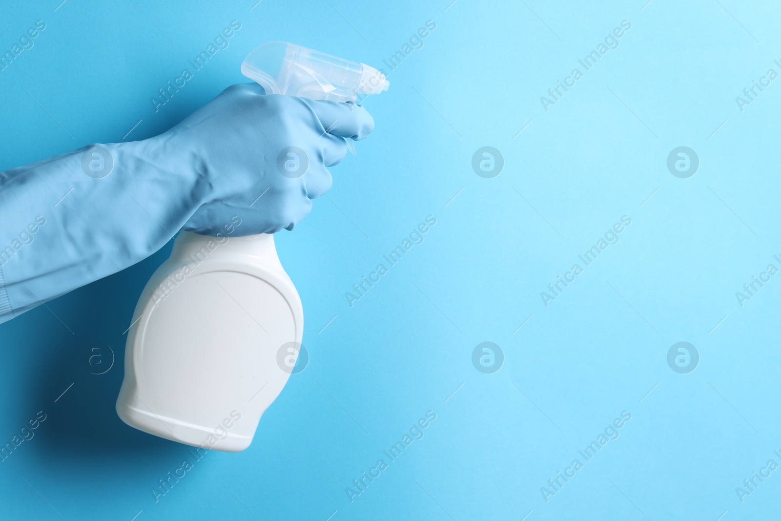 Photo of Woman with spray bottle of cleaning product on light blue background, closeup. Space for text