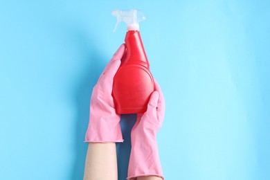 Photo of Woman with spray bottle of cleaning product on light blue background, top view