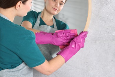 Photo of Woman cleaning mirror with rag indoors, closeup. Space for text