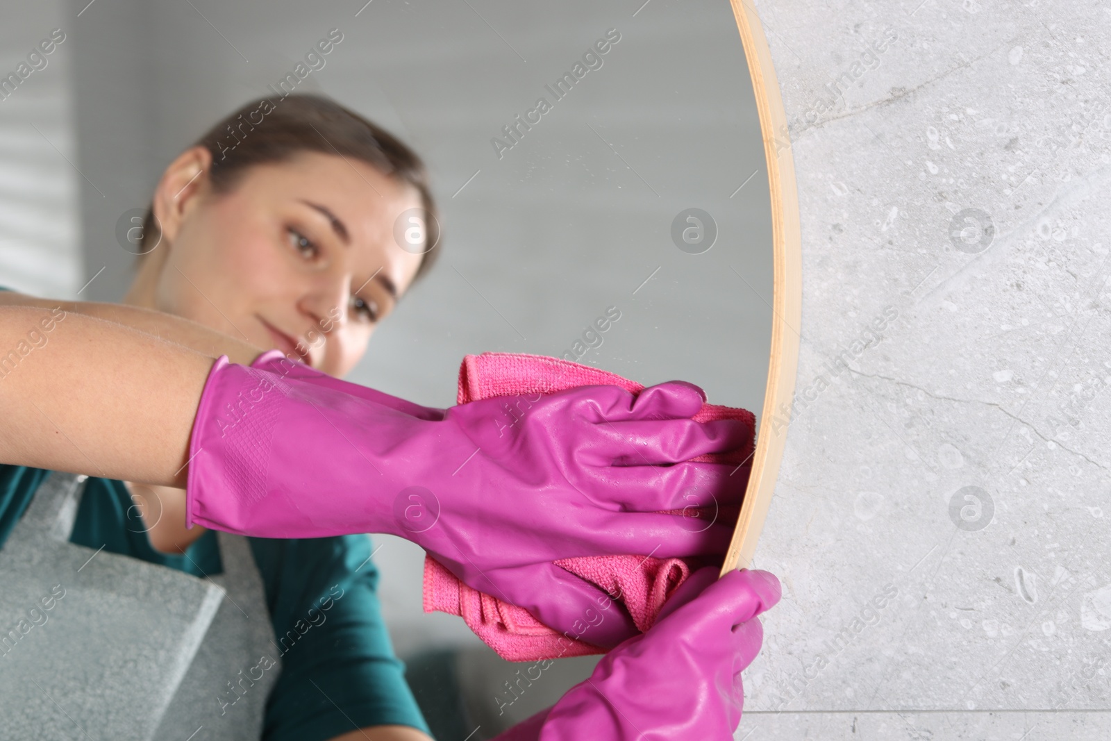 Photo of Woman cleaning mirror with rag indoors, selective focus