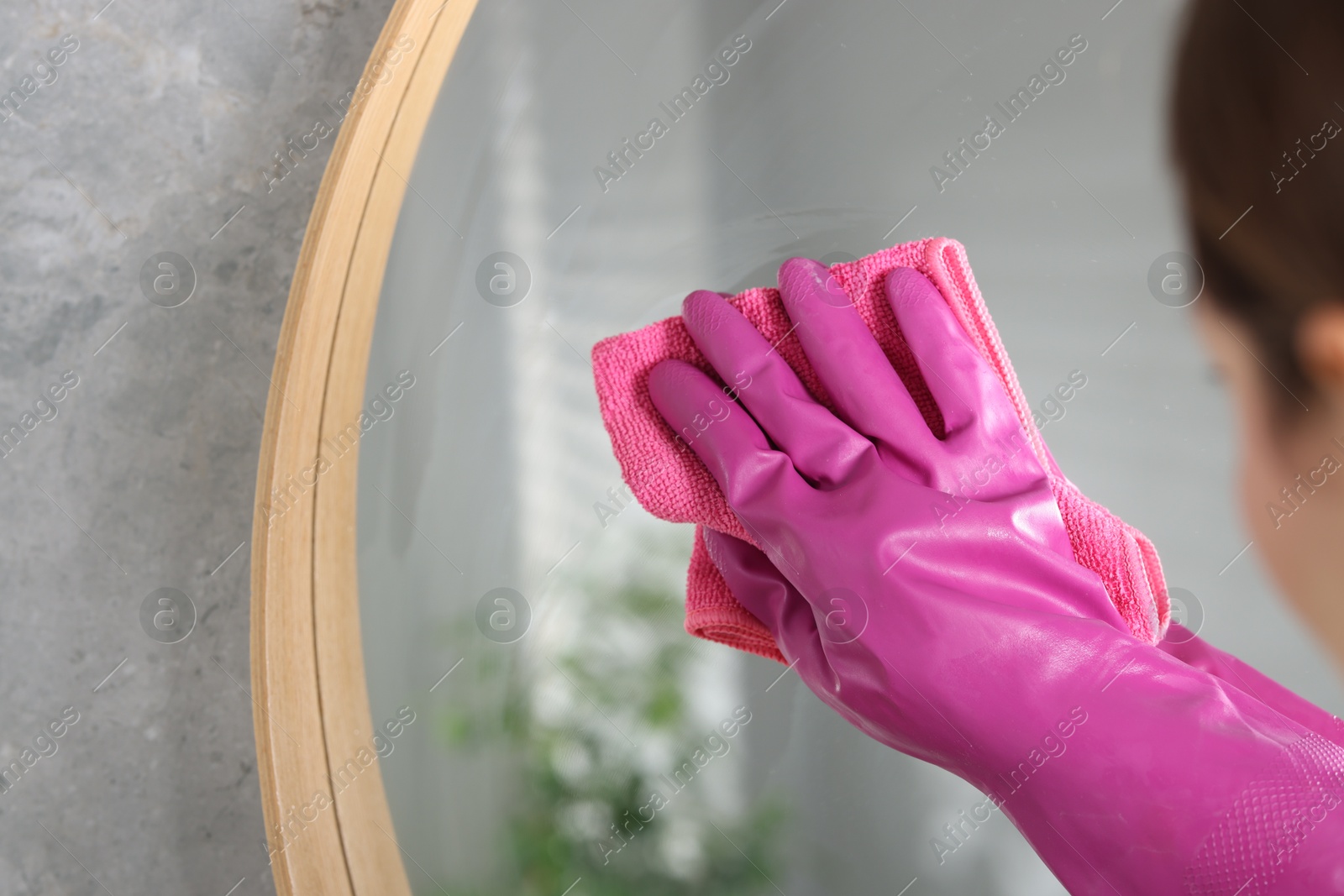 Photo of Woman cleaning mirror with rag indoors, closeup