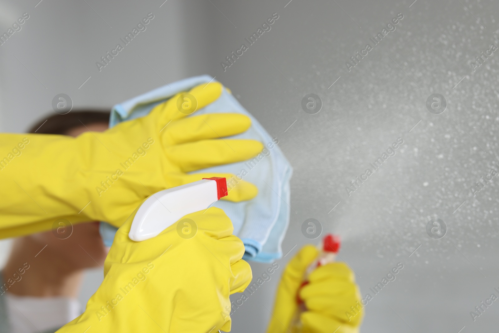 Photo of Woman using cleaning product while wiping mirror with rag indoors, closeup. Space for text