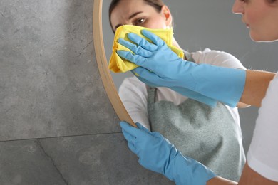 Photo of Woman cleaning mirror with rag indoors, space for text