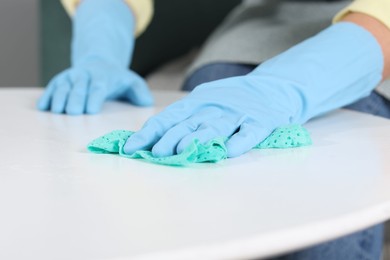 Photo of Woman cleaning table with rag indoors, closeup