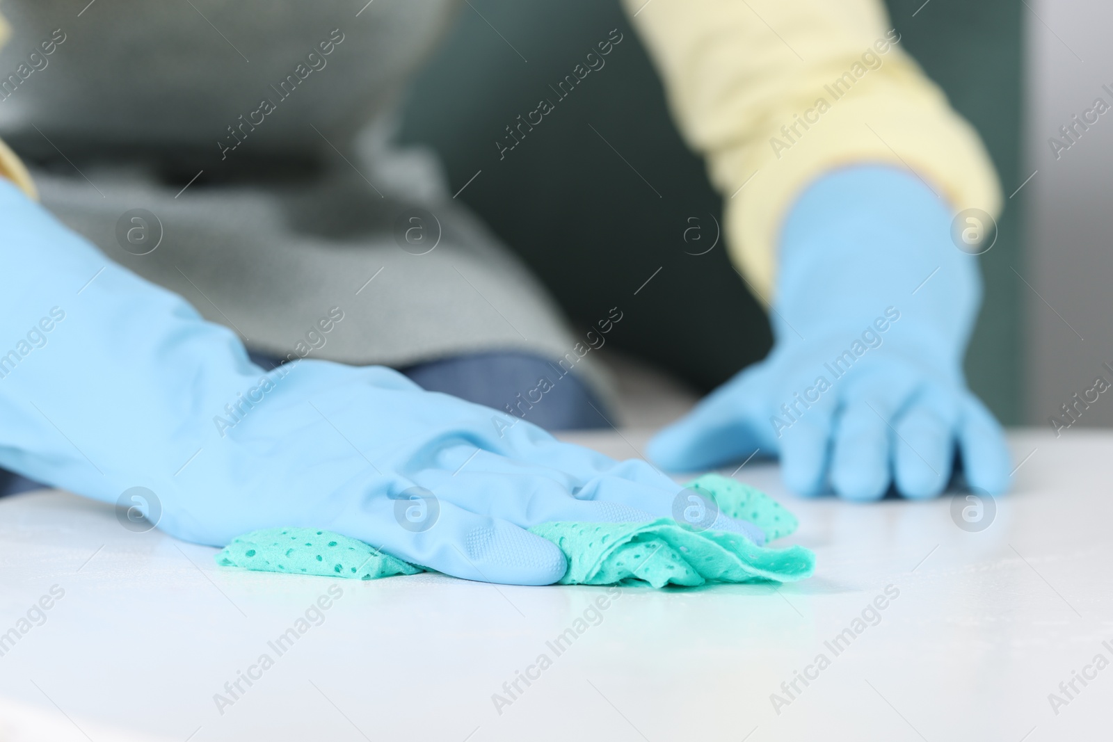 Photo of Woman cleaning table with rag indoors, closeup