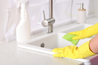 Photo of Woman cleaning sink with rag in kitchen, closeup