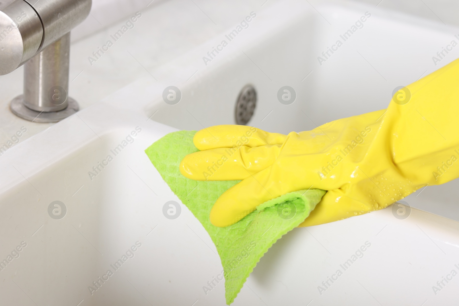 Photo of Woman cleaning sink with rag in kitchen, closeup