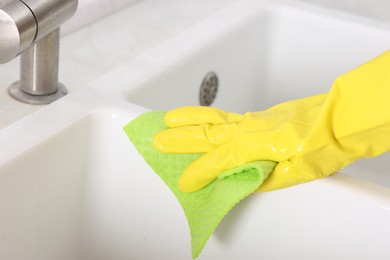 Photo of Woman cleaning sink with rag in kitchen, closeup