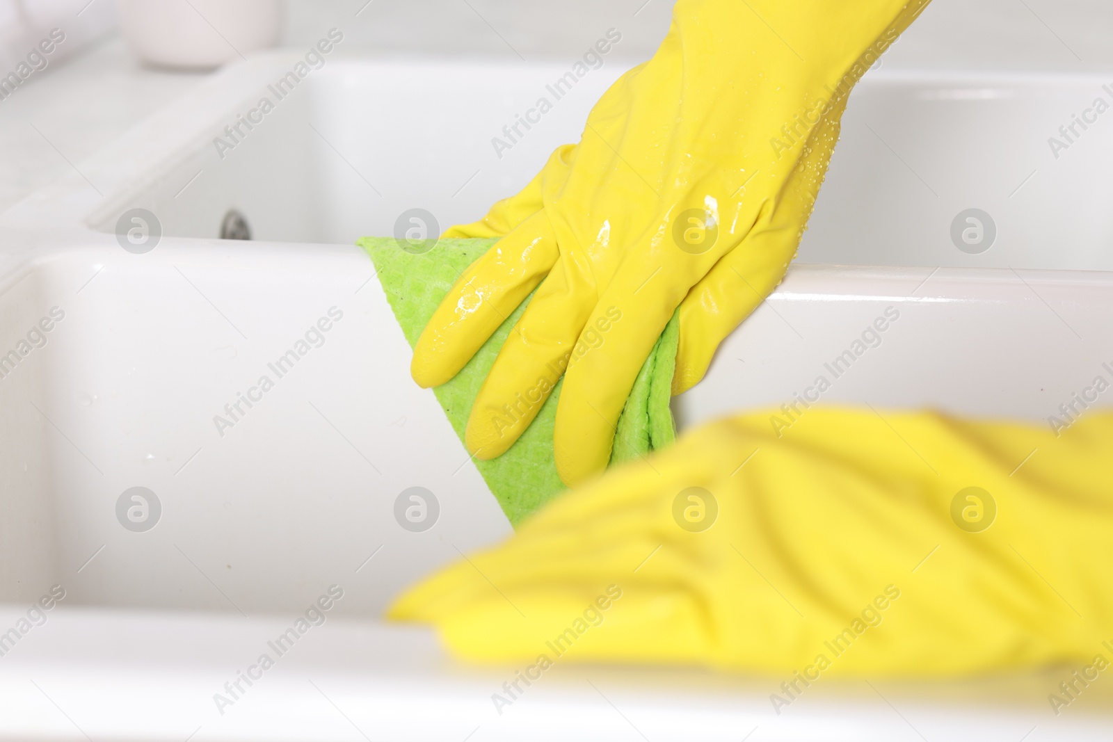 Photo of Woman cleaning sink with rag in kitchen, closeup