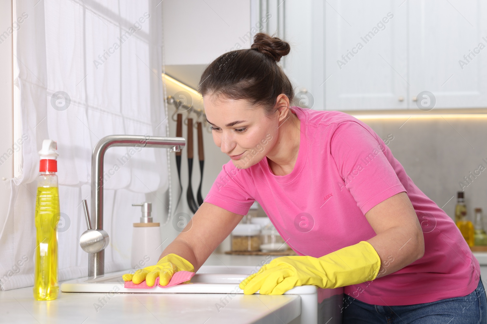 Photo of Woman cleaning sink with rag in kitchen